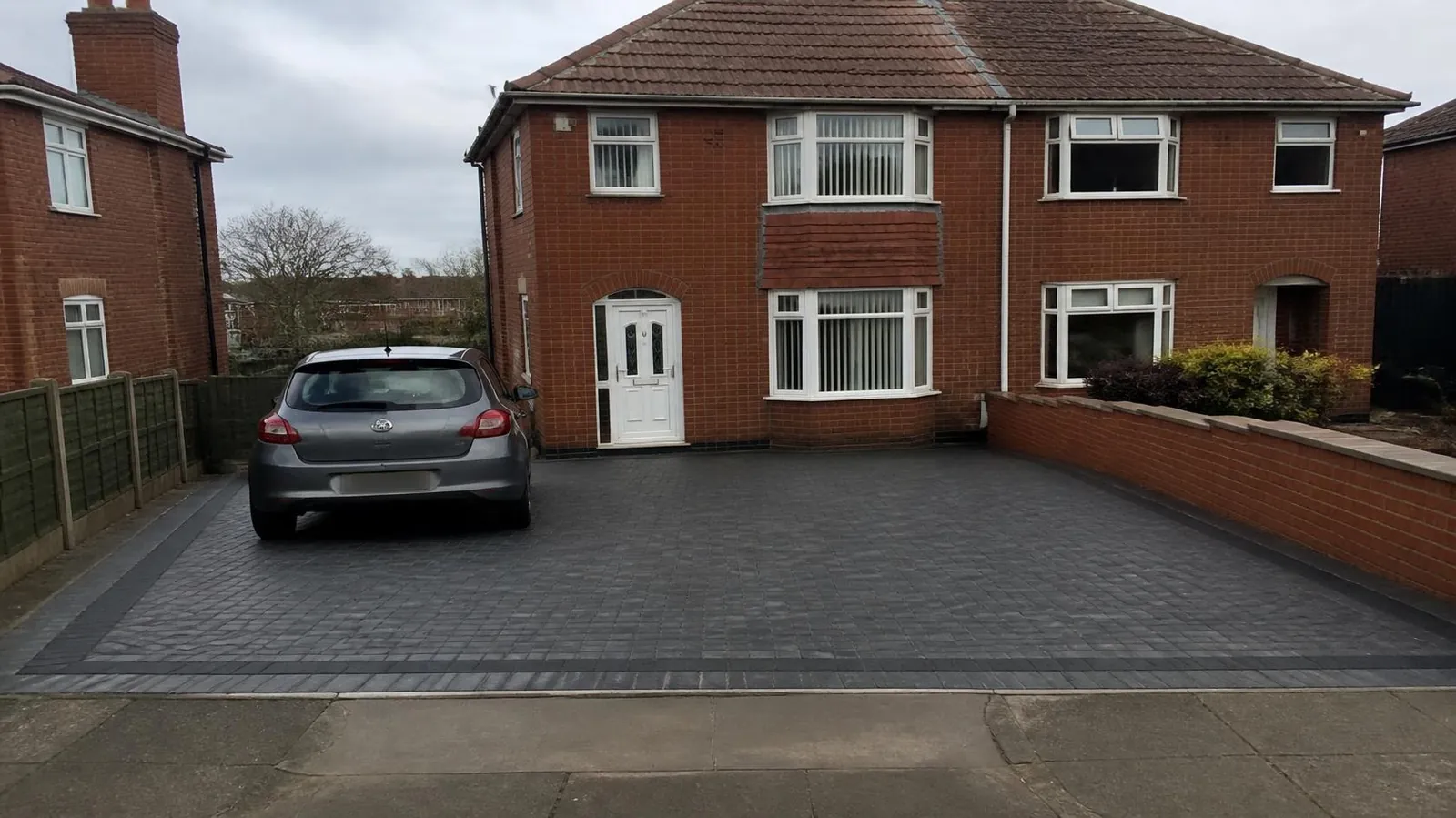 Block-paved driveway in grey blocks with a charcoal border in front of a brick house