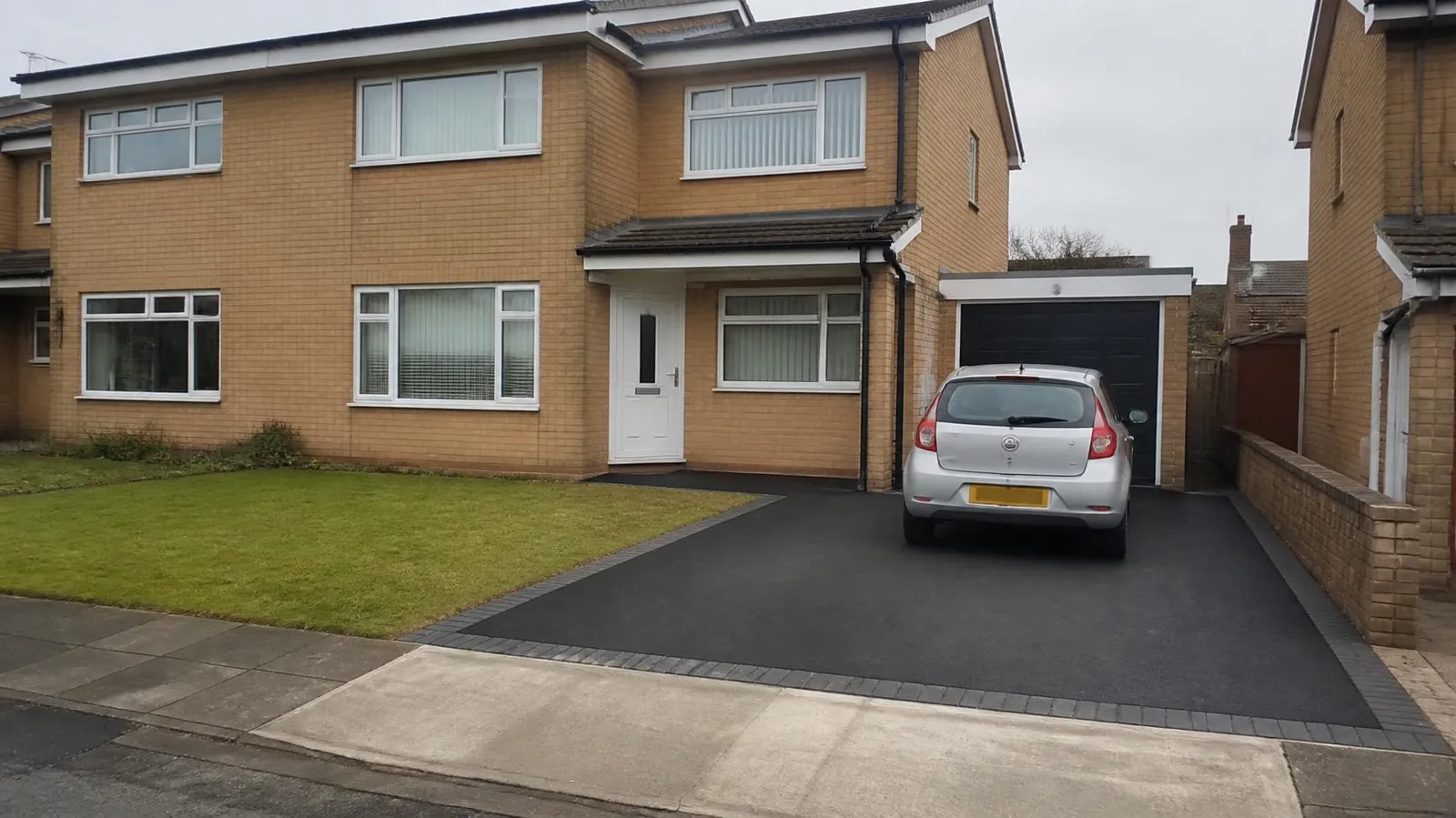 New black tarmac driveway with block edging in front of a semi-detached house